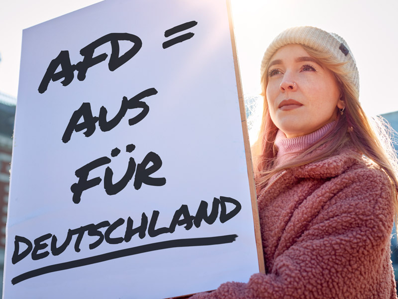 Eine Person hält ein Plakat gegen die AFD nach oben mit der Aufschrift: AFD Aus Für Deutschland